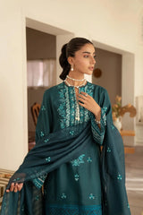 Woman wearing a teal embroidered outfit in an indoor setting